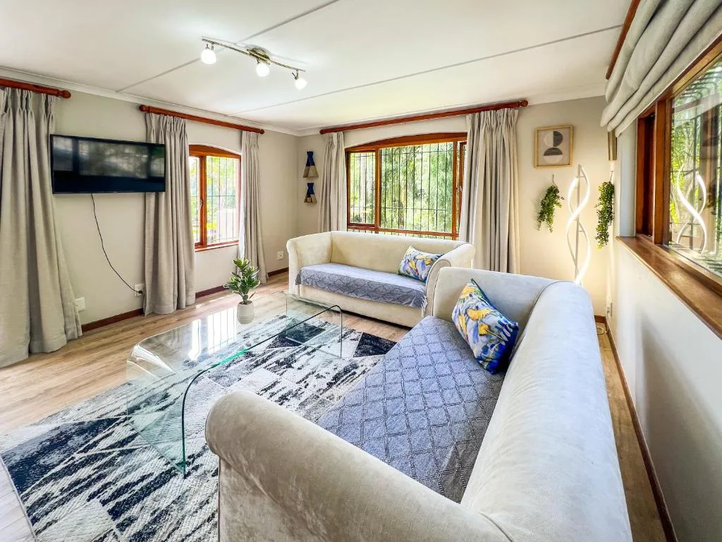 Bright lounge with cream sofas, TV, wooden floors, and garden views