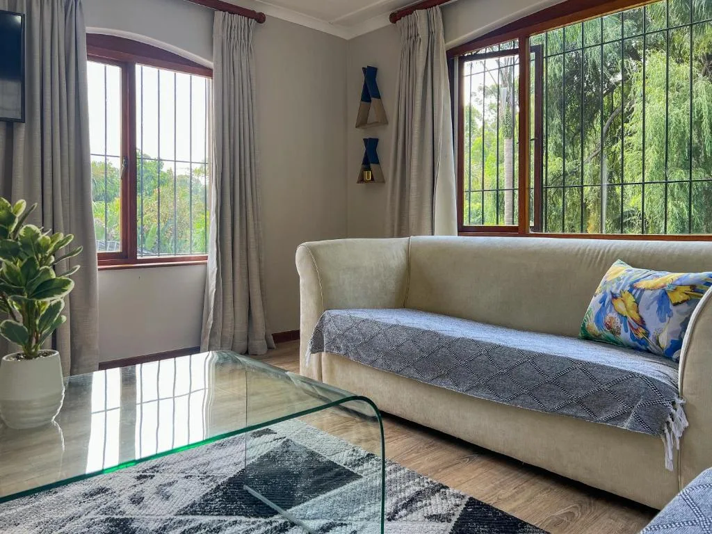 Bright living room with cream sofa, glass coffee table, and garden views