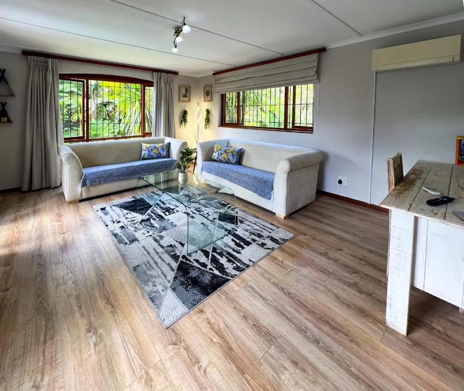 Bright lounge with two cream sofas, patterned rug, and garden views through windows