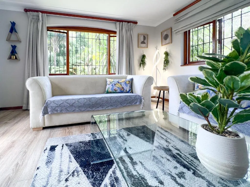 Bright lounge with cream sofa, glass table, potted plants, and garden views