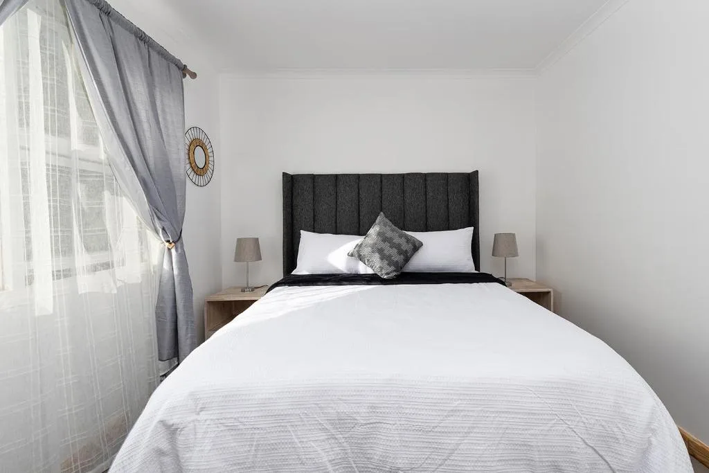 Modern bedroom with black upholstered headboard and white bedding