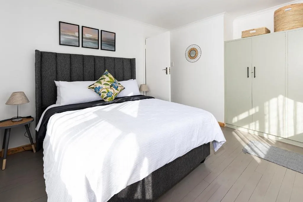 Bright bedroom with charcoal headboard, white bedding, and modern wardrobe