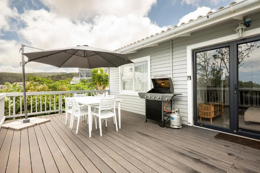 Spacious wooden deck with dining table, umbrella, and built-in braai area