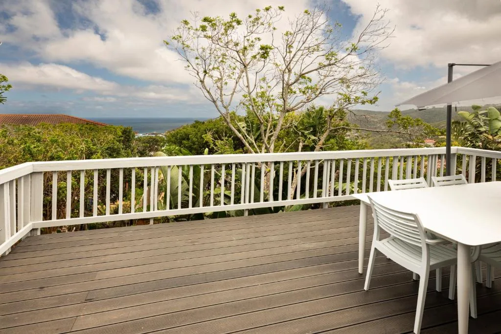 Spacious wooden deck with white railings overlooking coastal mountain views