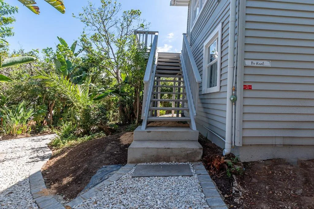 Garden Route home entrance with wooden stairs and tropical landscaping