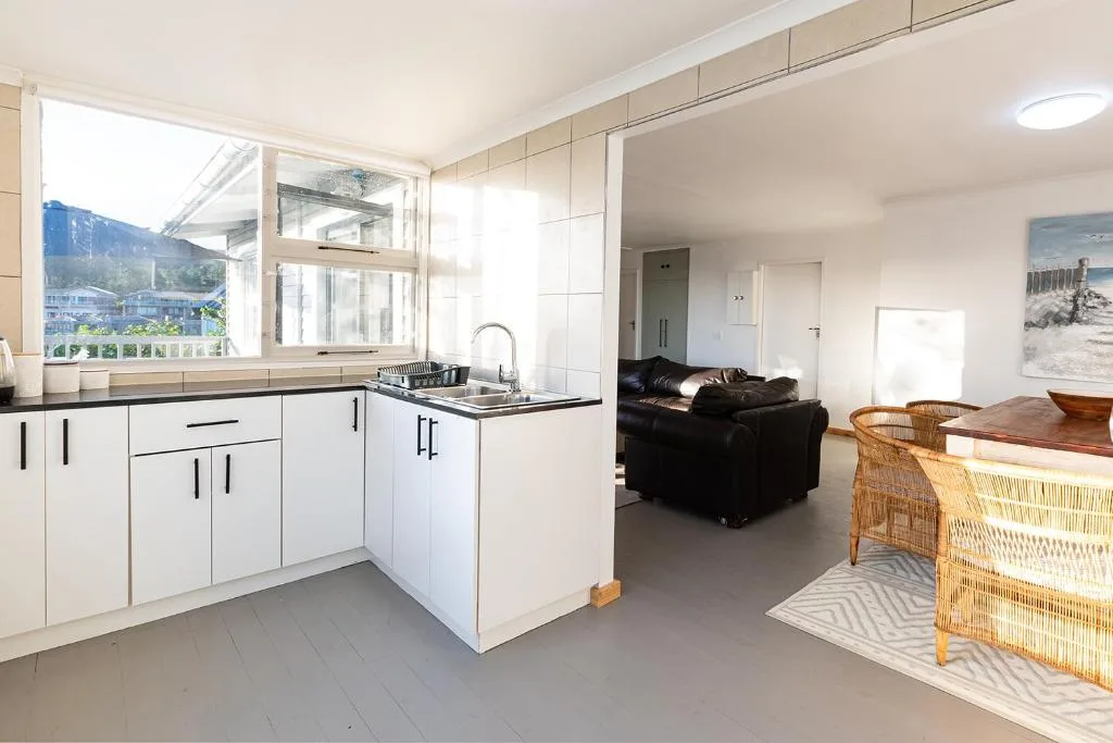 Modern white kitchen with black countertops and window overlooking mountains