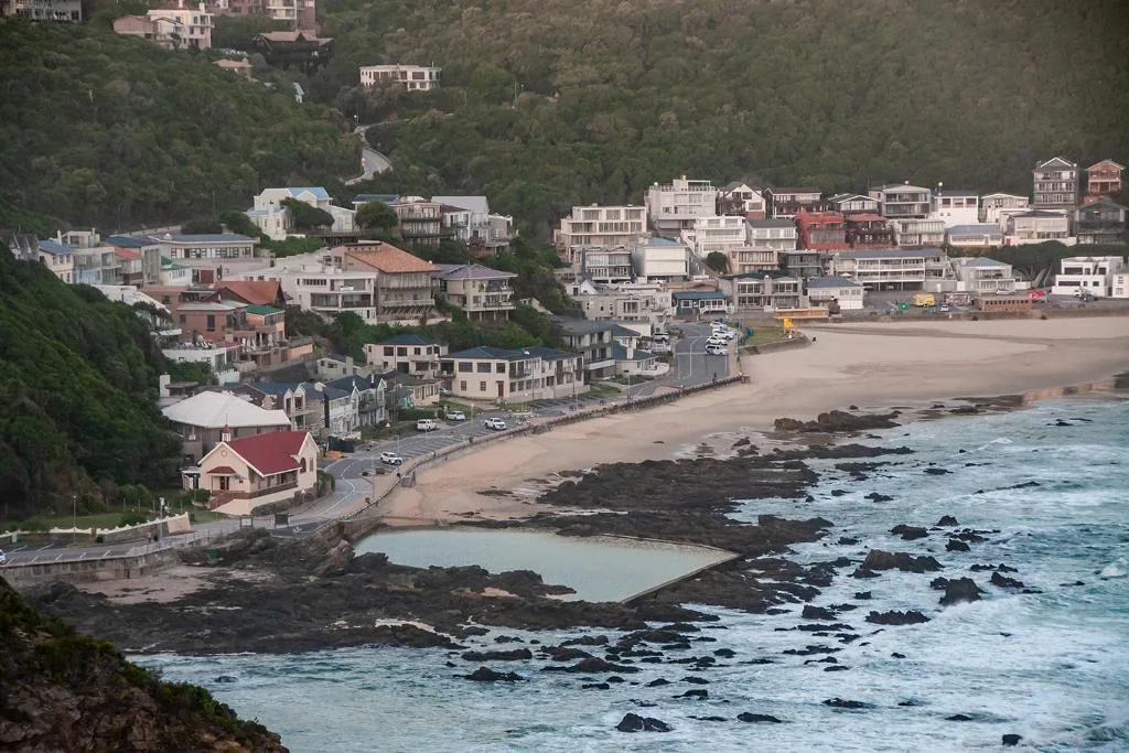 Coastal village nestled against forested hills with sandy beach