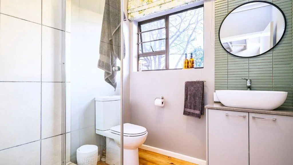 Modern bathroom with vessel sink, toilet, and green tiled accent wall