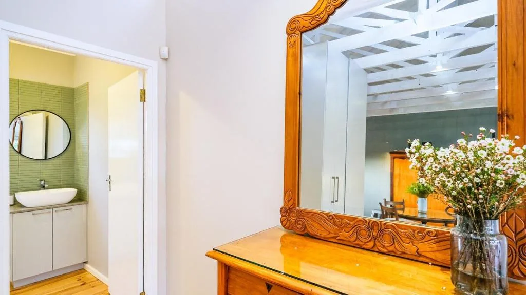 Bedroom with wooden dressing table, ornate mirror, and ensuite bathroom access