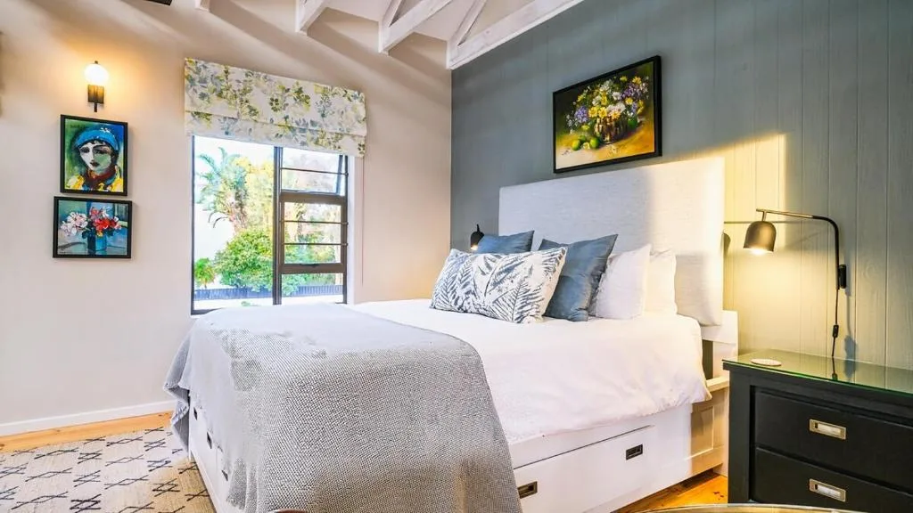 Bright bedroom with queen bed, artwork, and garden view through doors