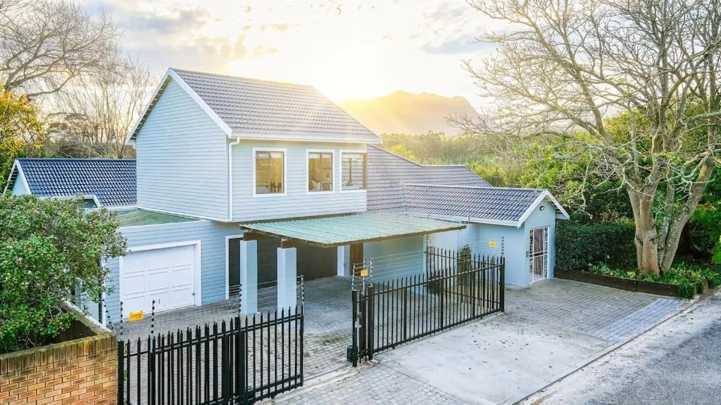 Modern white home with black metal gates and mountain backdrop