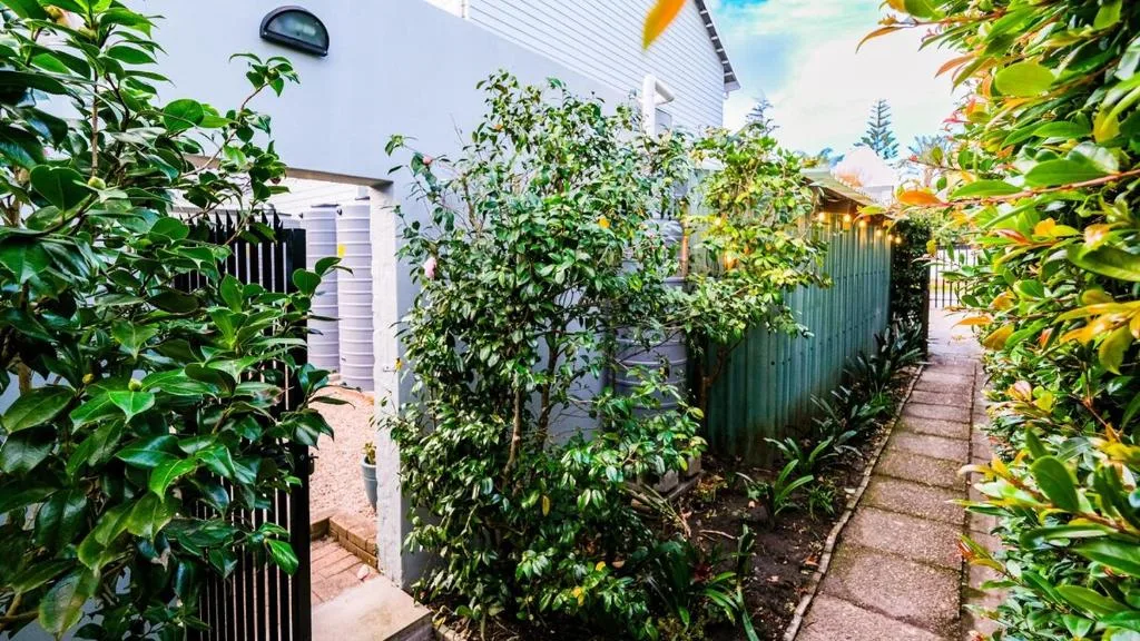 Garden pathway with lush green plants and white cottage exterior visible