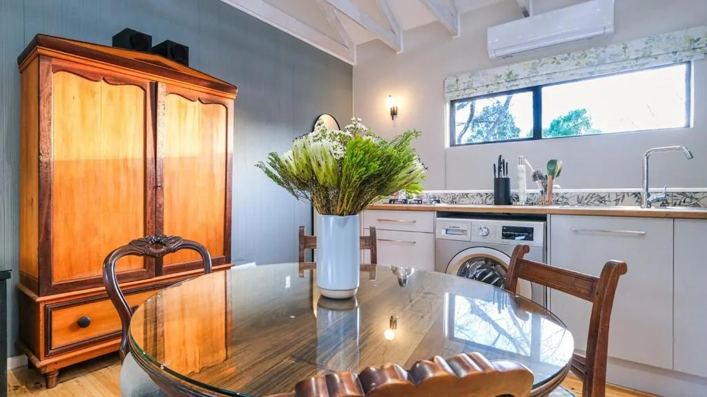 Modern kitchen with white cabinetry, dining table, and vintage orange wardrobe