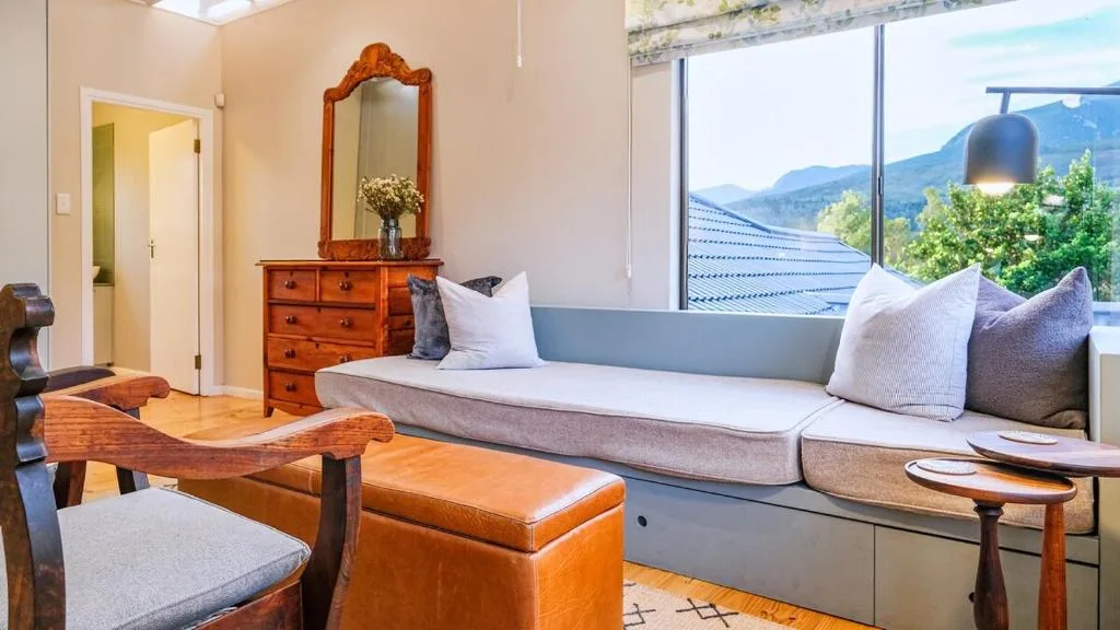 Bright lounge with gray sofa, wooden furniture, and mountain views through large windows