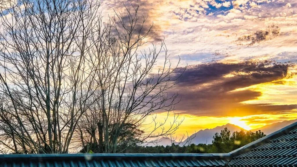 Dramatic sunset over mountains visible from property roofline