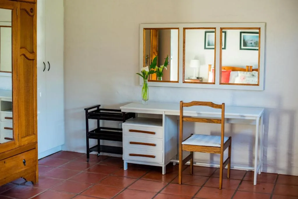 Bedroom with desk, wooden chair, and three-mirror vanity setup