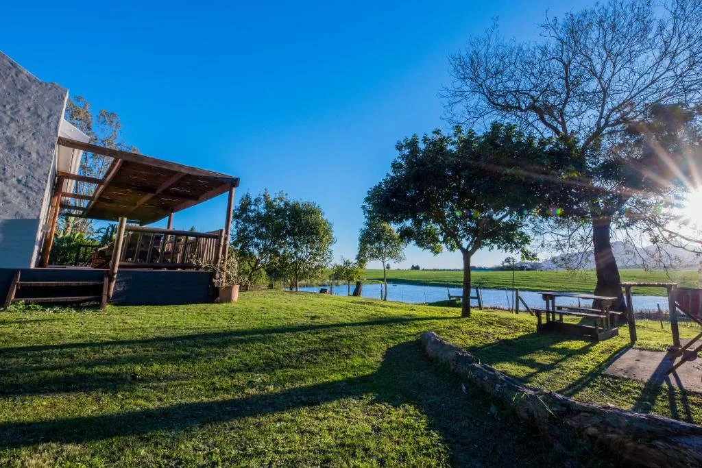 Wooden pergola deck with lawn overlooking lagoon and farmland