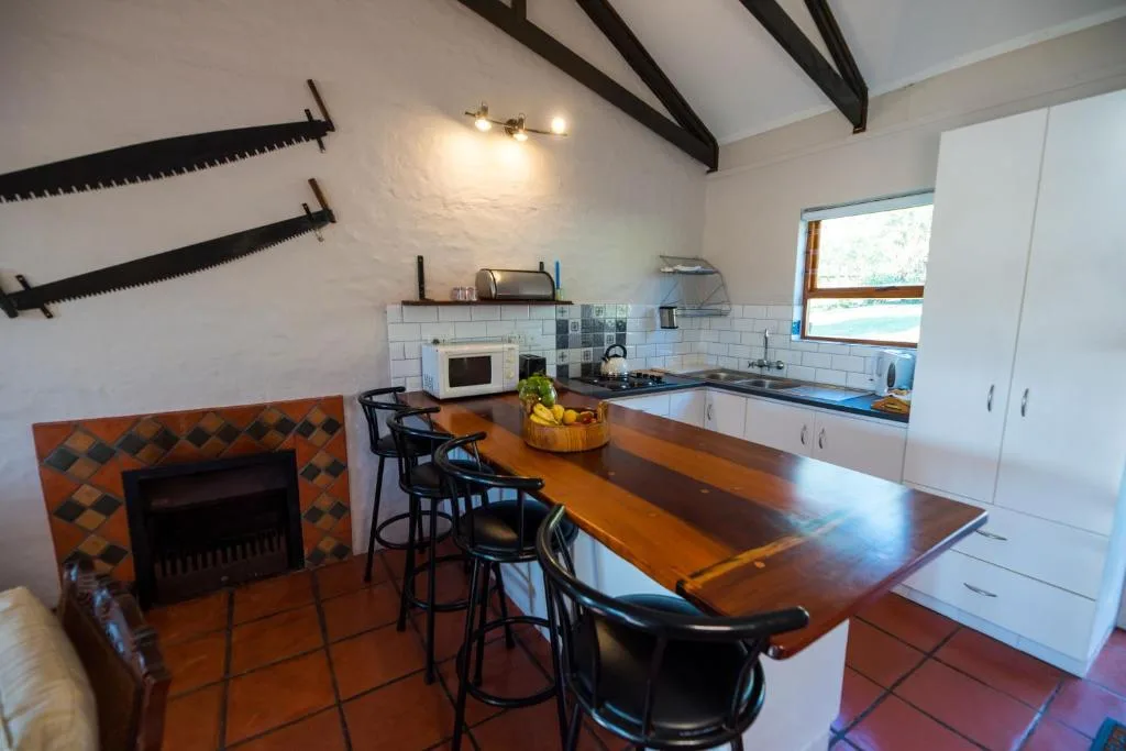 Open-plan kitchen with wood counter, white cabinetry, and black bar seating