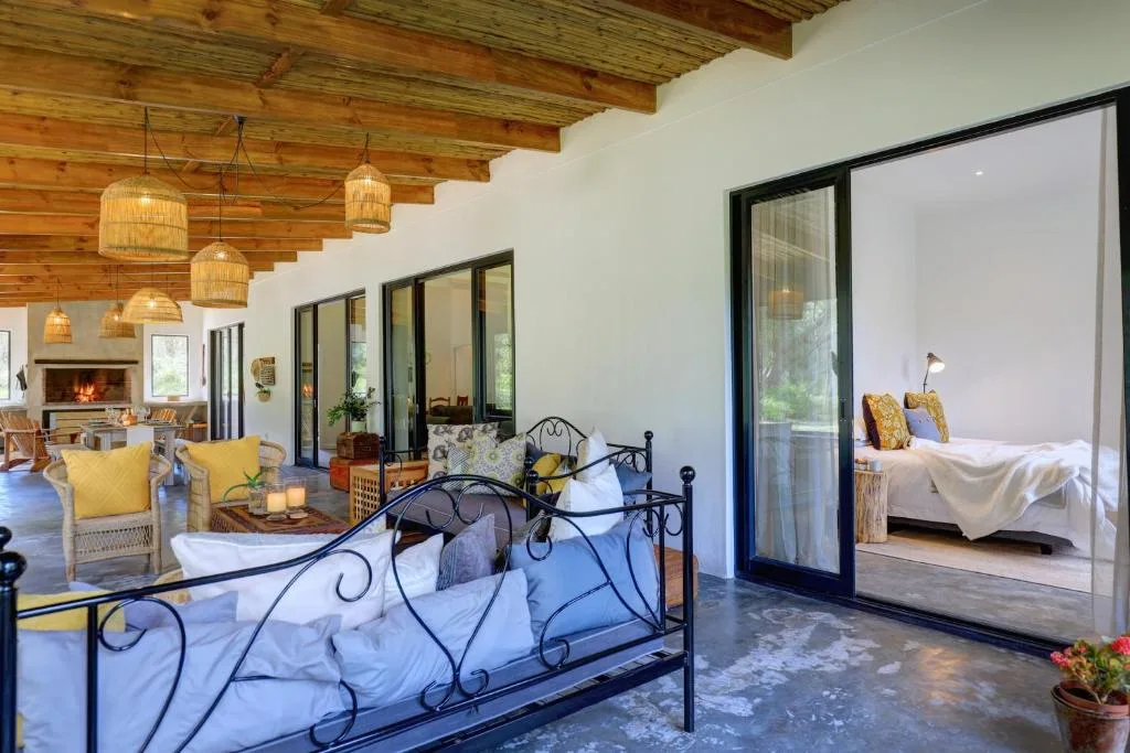 Spacious bedroom with ornate iron bed and open-plan lounge area visible