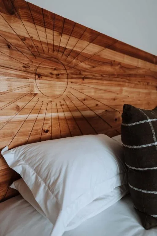 Bedroom with white pillow and carved wooden sun headboard