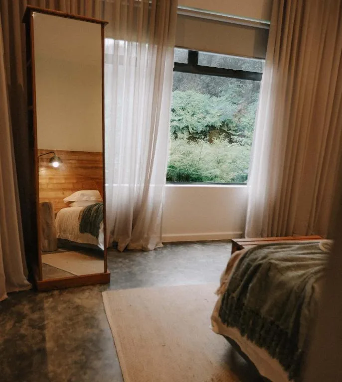 Spacious bedroom with twin beds, large mirror, and garden views through window