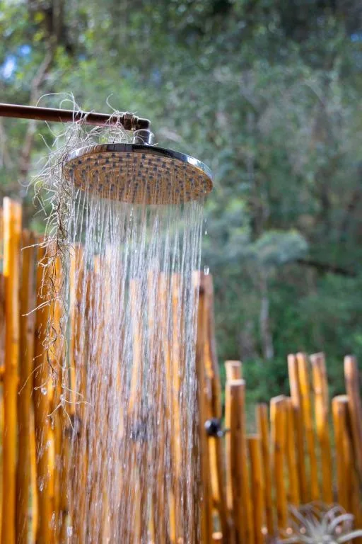 Outdoor shower head with water flowing over wooden screening backdrop