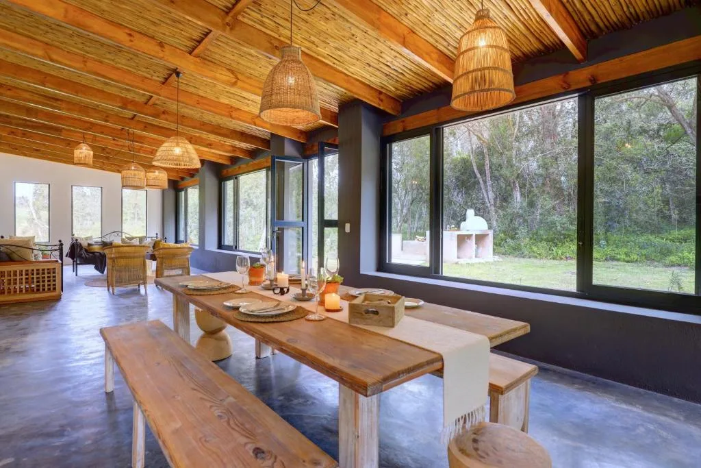 Open-plan dining area with wooden table and bench seating overlooking forest views
