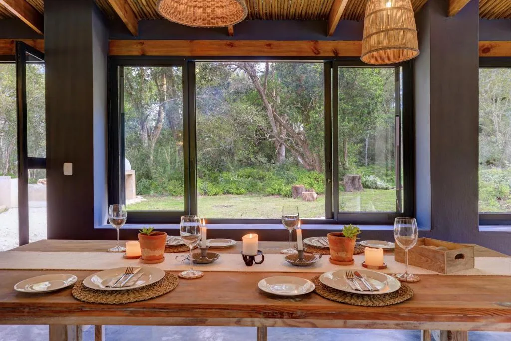 Elegant dining table set for four with forest views through large windows