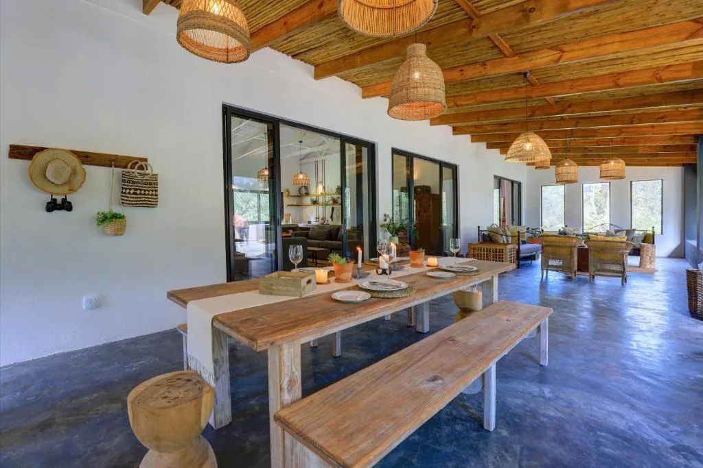 Spacious open-plan dining area with wooden table and benches, woven pendant lights