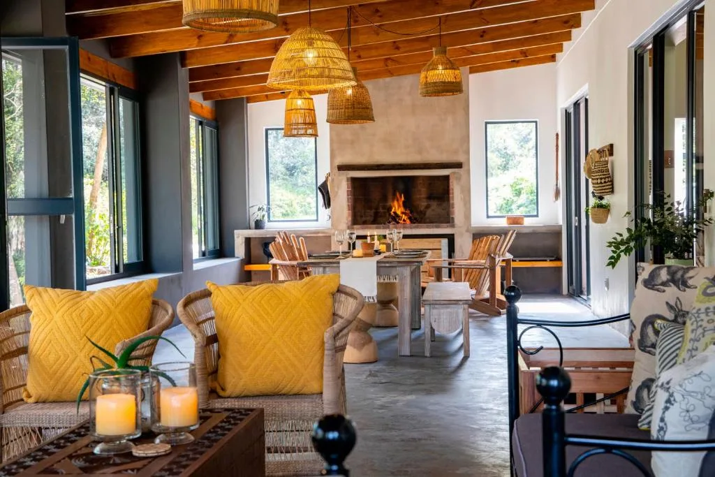 Spacious lounge with wicker chairs, yellow cushions, fireplace and wood beams