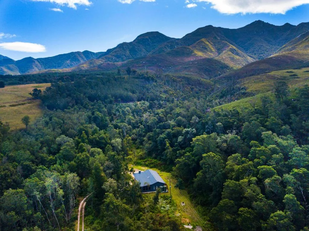 Aerial view of mountain-surrounded property nestled in lush forest valley