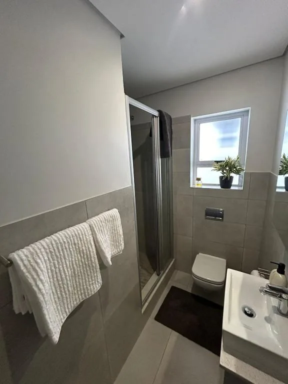Modern bathroom with shower, toilet, sink and heated towel rack