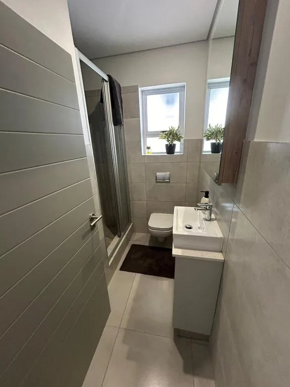 Modern bathroom with shower, toilet, sink vanity, and windows