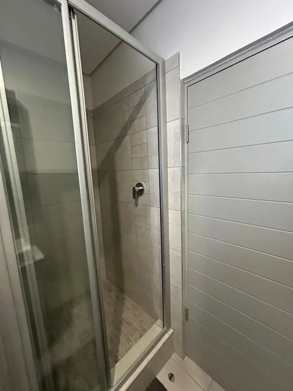 Modern shower enclosure with glass door and white tile walls