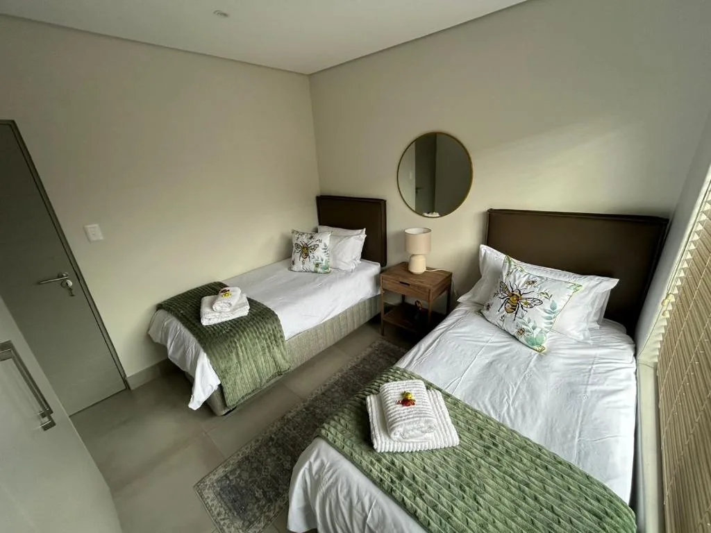 Twin bedroom with two single beds, round mirror, and soft green accents