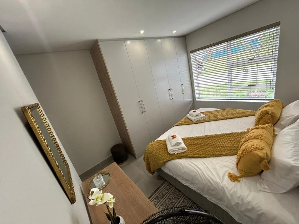 Modern bedroom with twin beds, gold accents, and built-in wardrobes