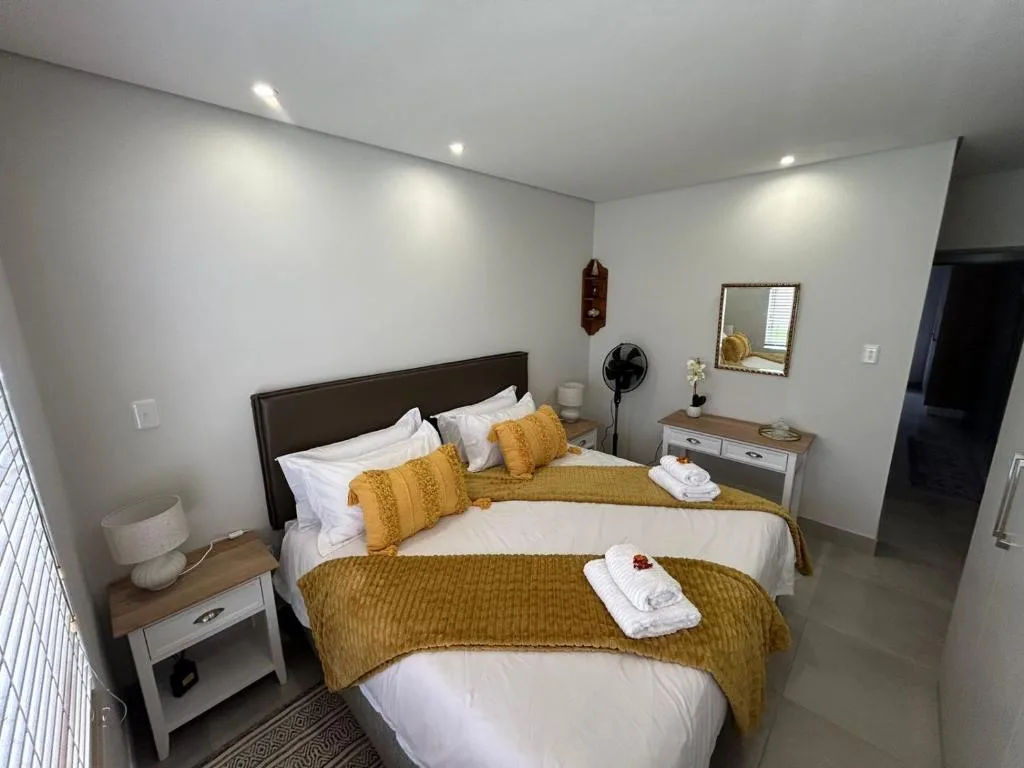 Spacious bedroom with queen bed, golden bedding, and modern furnishings