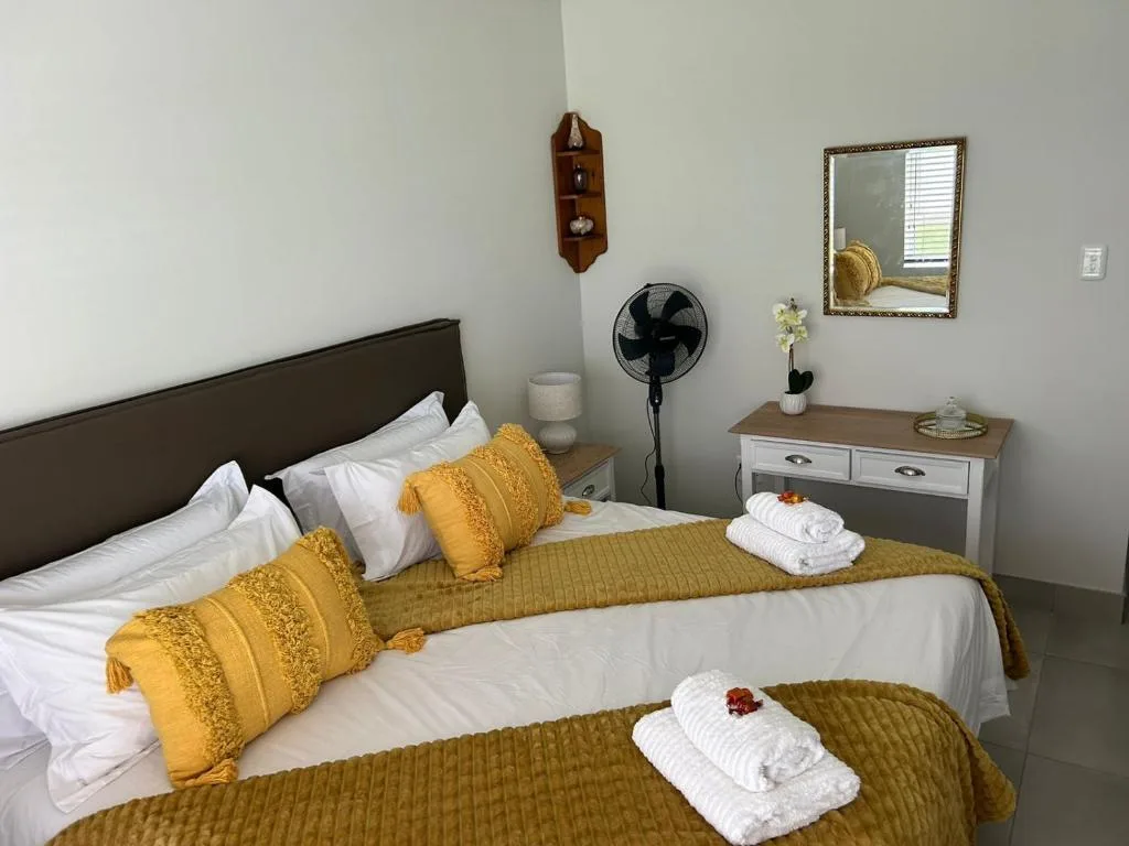 Bright bedroom with twin beds, gold accents, and white linens