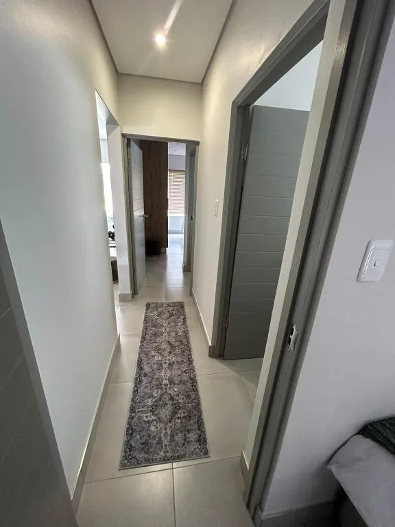 Modern hallway with neutral walls, grey doors, and patterned runner