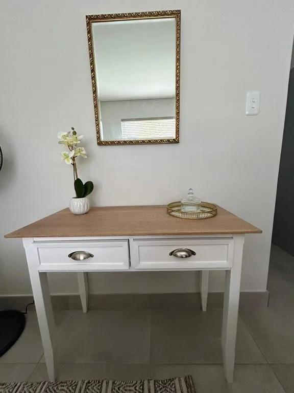 Vanity desk with ornate mirror, white drawers, and decorative orchid arrangement