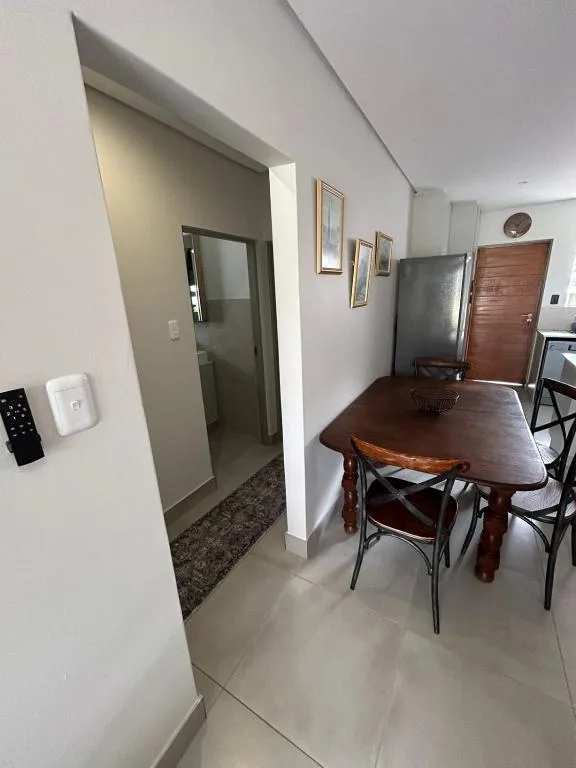 Dining area with wooden table and chairs, kitchen entrance visible