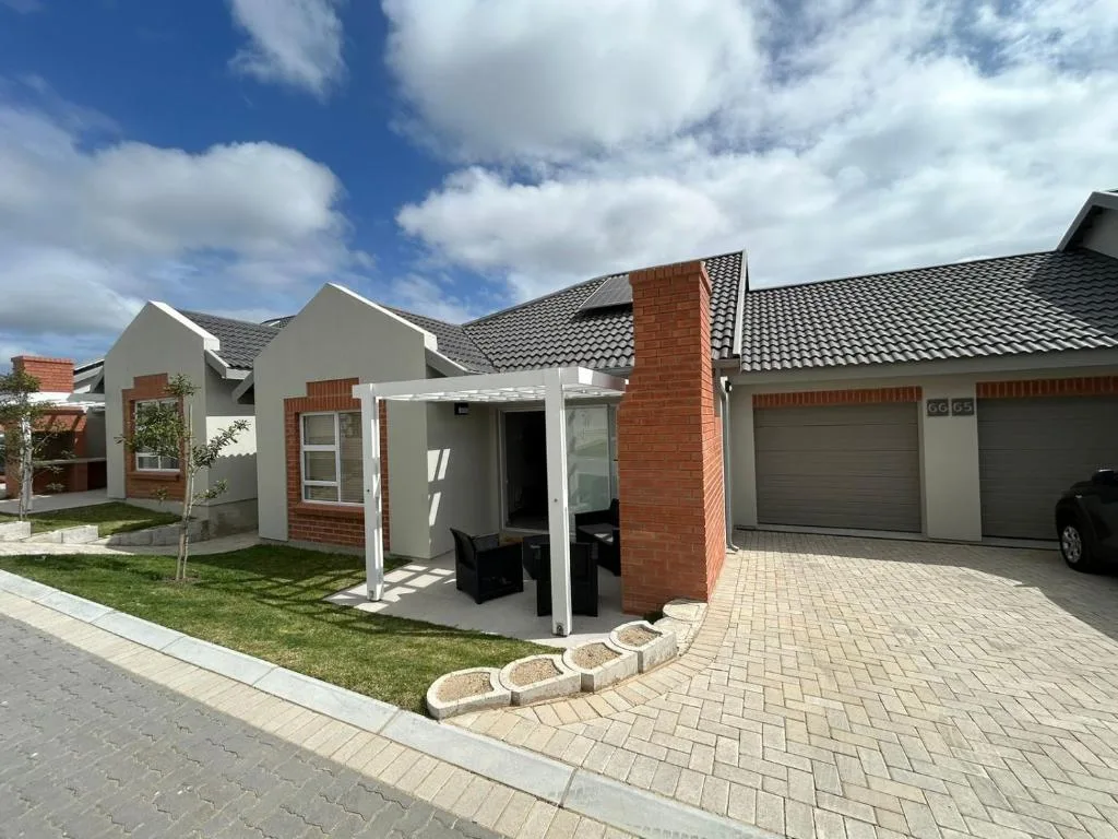 Modern white and brick home with garage and manicured lawn, clear sky
