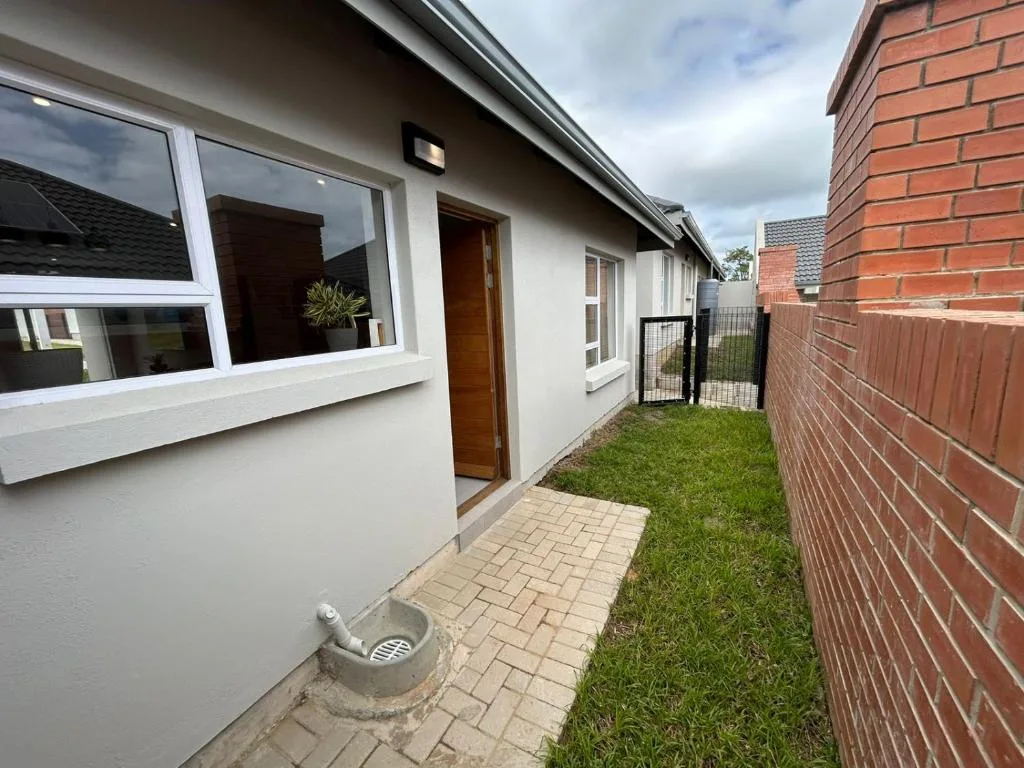 Modern white cottage exterior with paved pathway and manicured green lawn