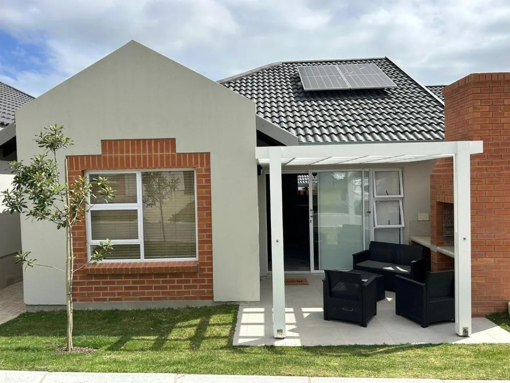 Modern brick and white rendered cottage with covered patio and solar panels