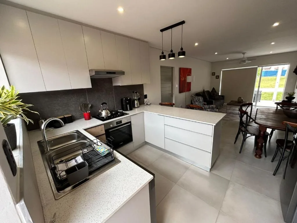 Modern open-plan kitchen with white cabinetry, stainless steel appliances, and island counter