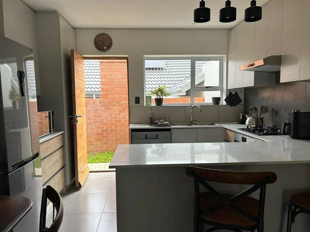 Modern kitchen with white counters, gray cabinetry, and brick exterior view