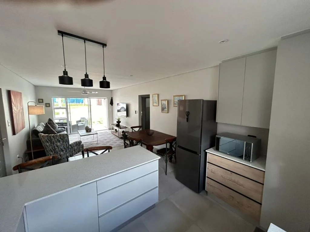 Modern open-plan kitchen with island bench, black refrigerator, and pendant lights