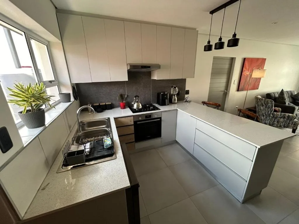Modern kitchen with white cabinetry, black backsplash, and stainless steel appliances