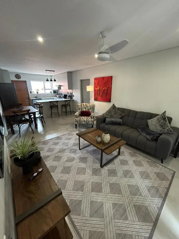 Modern living room with dark sofa, coffee table, and open-plan kitchen view