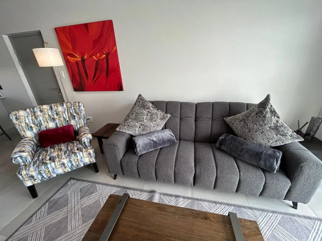 Modern lounge with gray sofa, patterned armchair, and red wall art